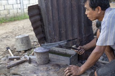 Luang Prabang, Laos - 8 Ekim: Çözgü Luang Prabang, Laos üzerinde 8 Ekim 2017 yılında köy demirhane bir bıçak kimliği belirsiz denetler.