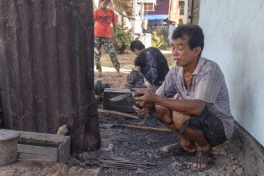 Luang Prabang, Laos - 8 Ekim: Kimliği belirsiz bir köy demirhane Luang Prabang, Laos üzerinde 8 Ekim 2017 yılında tutamaç içine tang yazdıktan sonra bir bıçak inceler.