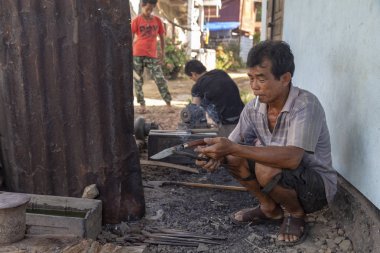 Luang Prabang, Laos - 8 Ekim: Luang Prabang, Laos üzerinde 8 Ekim 2017 yılında köy demirhane bir sigara bıçak kimliği belirsiz bakar.
