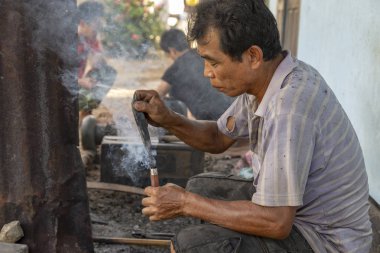 Luang Prabang, Laos - 8 Ekim: Kimliği belirsiz bir tutamaç Luang Prabang, Laos üzerinde 8 Ekim 2017 yılında köy demirhane içine bir bıçak yakar.