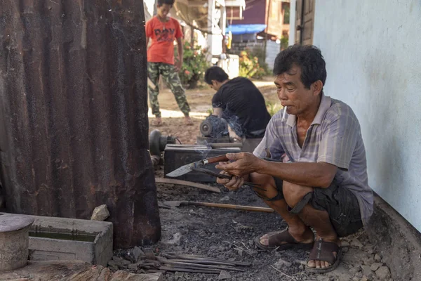 Luang Prabang, Laos - 8 Ekim: Luang Prabang, Laos üzerinde 8 Ekim 2017 yılında köy demirhane bir sigara bıçak kimliği belirsiz bakar.