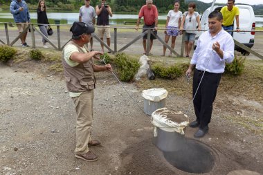 Furnas, Portekiz - 4 Ağustos: Tanımlanamayan bir şef ve onun yardımcısı kazmak dışarı Cozido, bir Azores yemek yere yakın Fumarolas da Lagoa das termal bacalarda Furnas Furnas, Portekiz 4 Ağustos 2017 üzerinde pişmiş.