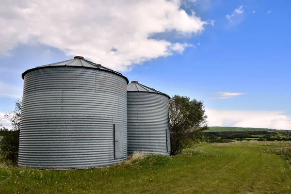 An image of two large grain silos in a field.