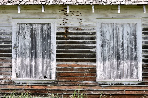 An image of old worn and weathered windows with broken glass.