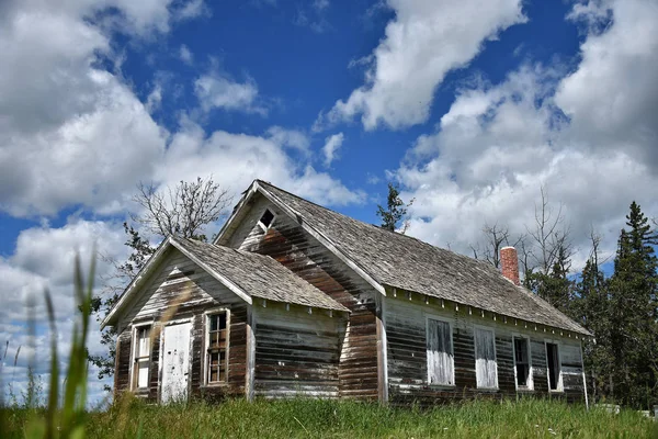 An image of an old weathered and run down farmhouse under a brilliant blue sky.