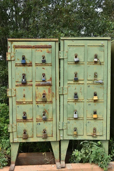 An image of old rusted green mailboxes and padlocks.