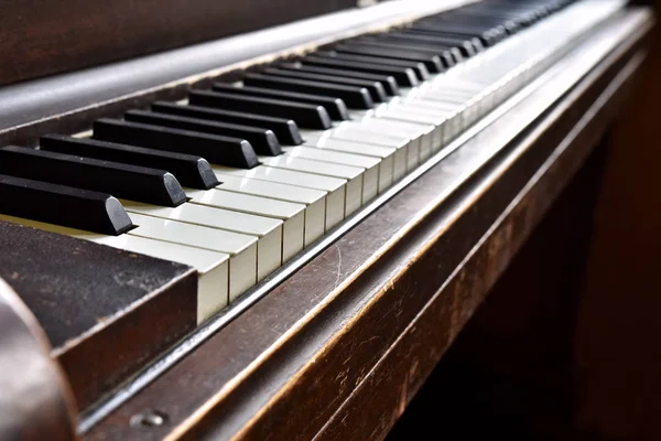 A low angle image of the keys on an old vintage upright piano.