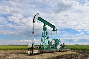 Bulutlu bir günde bir çalışma petrol kuyusu pompa jakına bir görüntü. 
