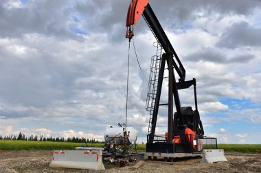 Bulutlu bir günde bir çalışma petrol kuyusu pompa jakına bir görüntü. 