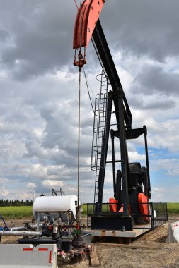Bulutlu bir günde bir çalışma petrol kuyusu pompa jakına bir görüntü. 