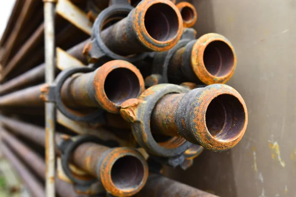 An abstract image of old rusted industrial pipes on a rack.