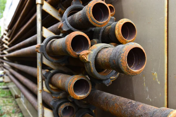 An abstract image of old rusted industrial pipes on a rack.