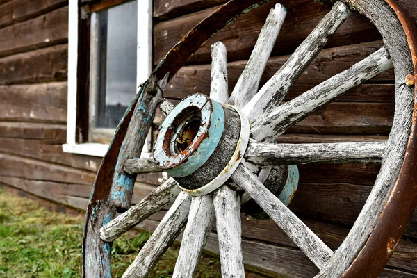 丸太小屋の側に傾いた古い木製のワゴン ホイールのイメージに近い — ストック写真