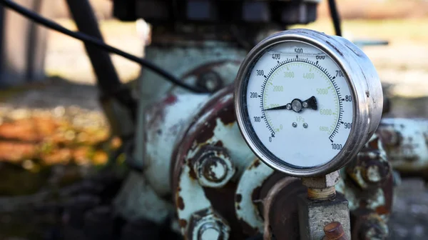 A close up image of an old industrial pressure gauge used in the oil and gas industry.