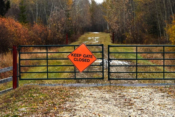 An image of a brightly colored sign posted to a metal gate indicating to keep the gate closed.