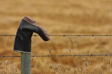 Eski ahşap çit mesaj bir çakıl yol tarafındaki üst kısımları çivilenmiş lastik çizme yıpranmış bir görüntü. 