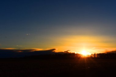 Geç sonbaharda altın bir günbatımı kesilmiş saman alanın üzerinde bir görüntü. 