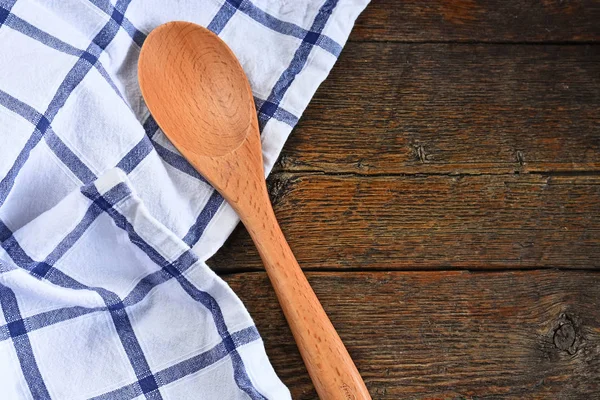 An image of wooden mixing spoons and colorful table cloth on an old style country kitchen table top.