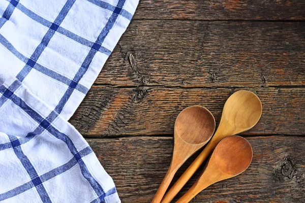 An image of wooden mixing spoons and colorful table cloth on an old style country kitchen table top.