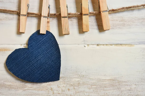 A close up image of several heart shaped symbols hung by clothes pins on a wooden background.