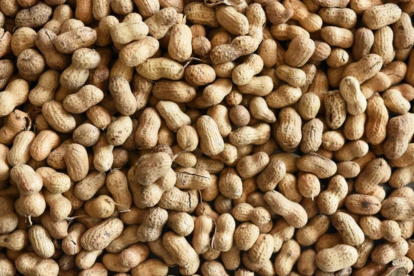 A close up image of roasted peanuts in the shell.
