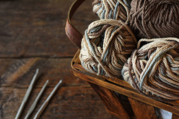 A close up image of crochet yarn and crochet hooks on a vintage wooden table. 