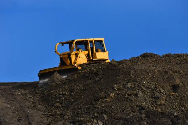 Bir şantiyede kir yığınının üstünde büyük sarı bir toprak mover bir görüntü. 