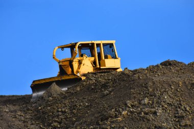 Bir şantiyede kir yığınının üstünde büyük sarı bir toprak mover bir görüntü. 
