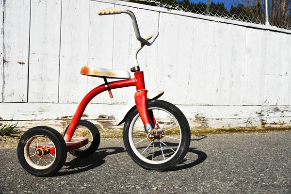 一辆旧红色三轮车在空荡荡的学校操场上的形象 — 图库照片