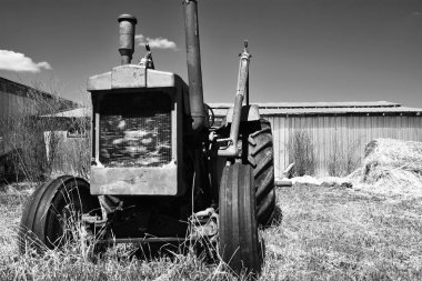 Eski bir çiftlik traktöraşağı çalıştırmak siyah beyaz görüntü. 