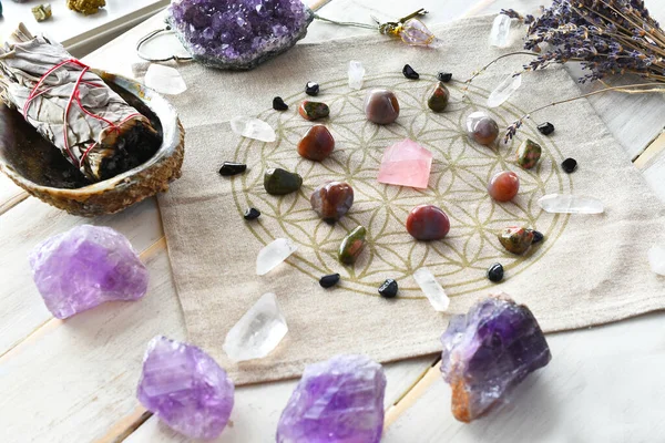 A close up image of a self love crystal grid using the flower of life sacred geometry grid cloth and amethyst crystals.