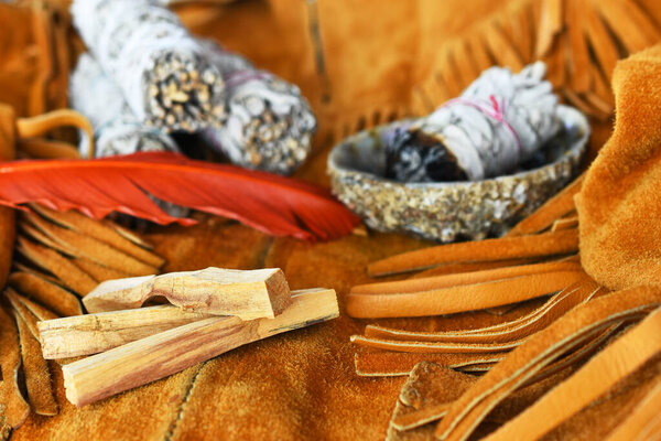 An image of three palo santo smudge sticks and white sage on an old vintage leather coat. 