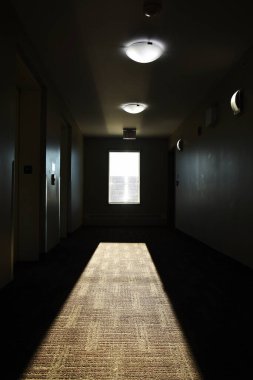 Çökmüş bir apartmanın karanlık bir koridorundaki pencereden süzülen güneş ışığının görüntüsü.. 