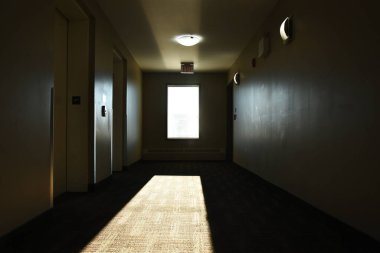 Çökmüş bir apartmanın karanlık bir koridorundaki pencereden süzülen güneş ışığının görüntüsü.. 