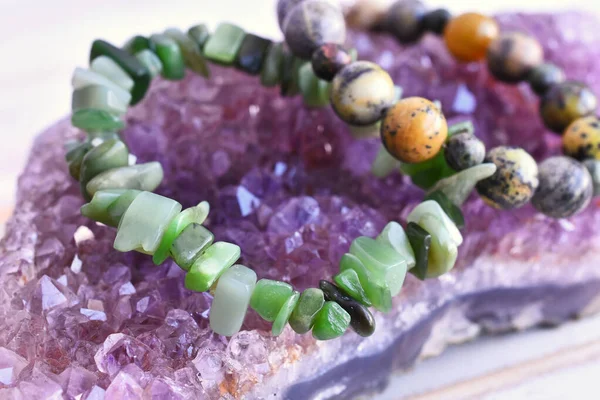 A close up image of an energy healing bracelet charging on a amethyst geode cluster.
