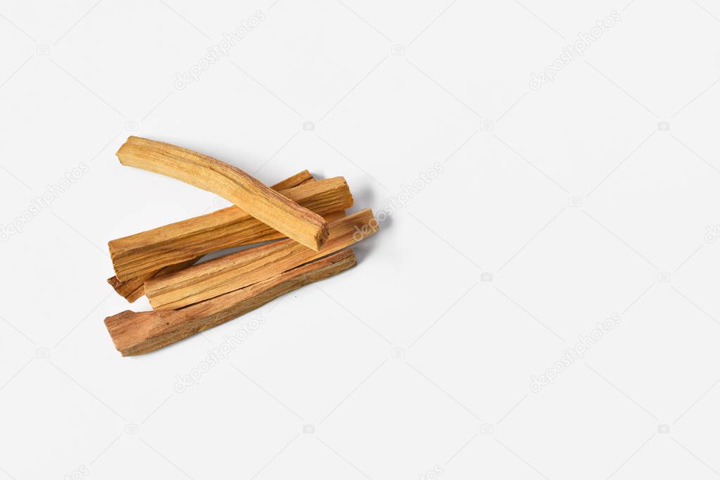 A top view image of several sticks of palo santo wood on a white background. 