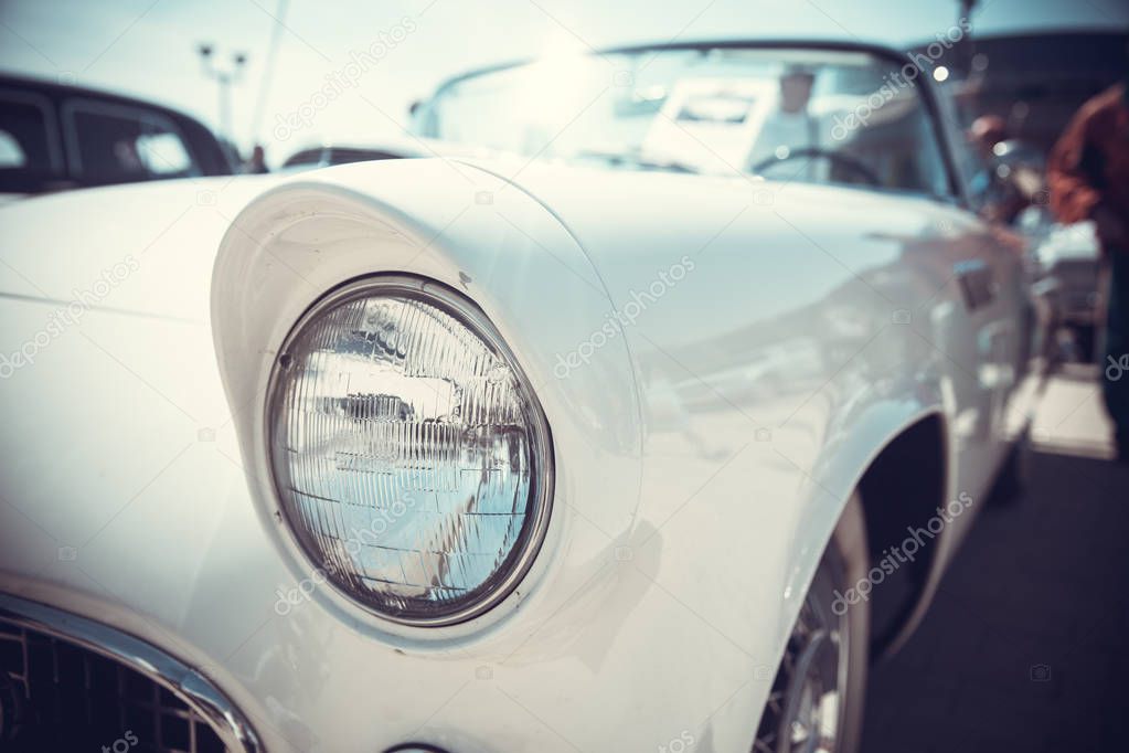 close up front view of old classic car headlight is outdoor with bokeh background