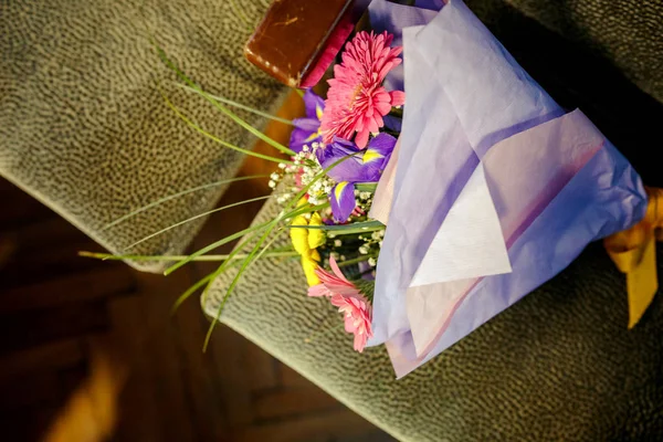 bouquet of flowers and a lady\'s handbag on the armchair