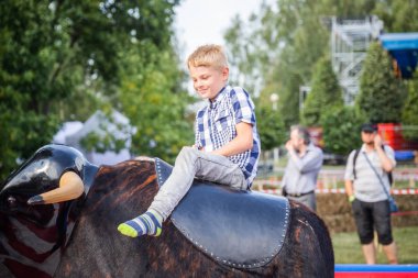 Minsk, Beyaz Rusya - 1 Mayıs 2017: Bir çocuk güvenli bir Mekanik boğaya eğlence sürüş sarılı iken adrenalin sahiptir