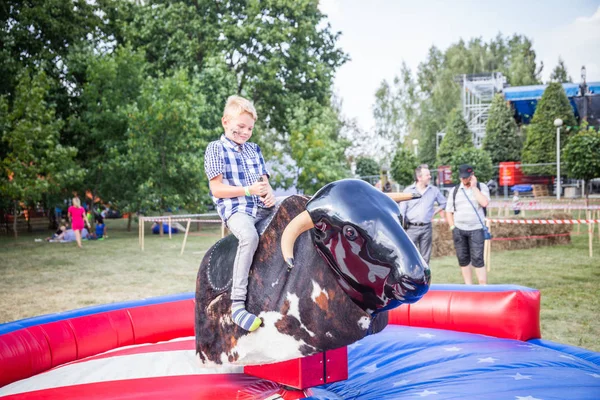 Minsk, Beyaz Rusya - 1 Mayıs 2017: Bir çocuk güvenli bir Mekanik boğaya eğlence sürüş sarılı iken adrenalin sahiptir
