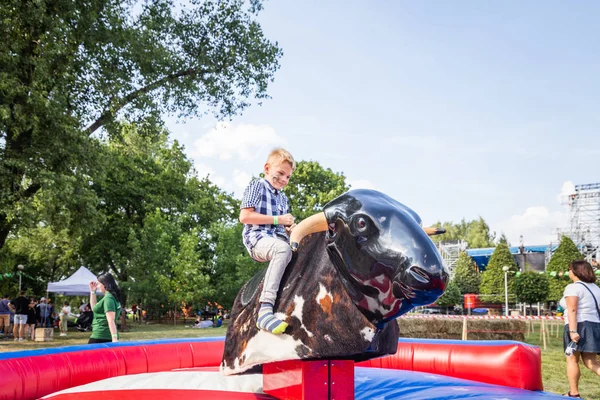 Minsk, Beyaz Rusya - 1 Mayıs 2017: Bir çocuk güvenli bir Mekanik boğaya eğlence sürüş sarılı iken adrenalin sahiptir