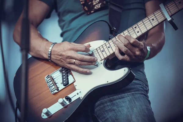 rock musician holding a guitar and playing it