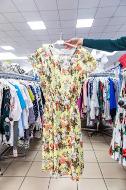 el bir giyim mağazasında elbise tutar