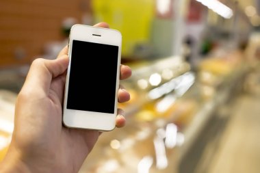 Mobil akıllı telefon süpermarket üzerinde tutan adam el bulanıklık arka plan, iş kavramı