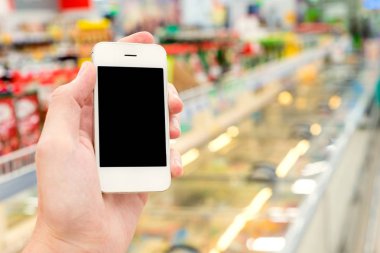 Mobil akıllı telefon süpermarket üzerinde tutan adam el bulanıklık arka plan, iş kavramı