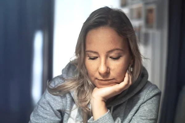 Evde, iskemlede, aşağı bakıyor ve kafasını kolunda döşeme dalgın kadın