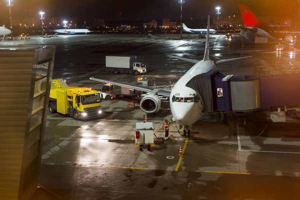 aircraft parked at the airport and preparation for next flight. Loading cargo on the plane in airport terminal at night. Workers cargo airplane service.