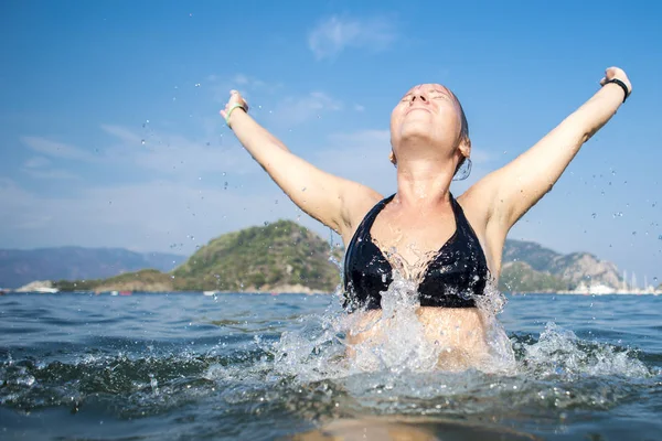 Woman happy jump sea waves splash in tropics on vacatio