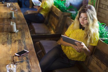 Tablet ile güzel kız bir kafede oturuyor