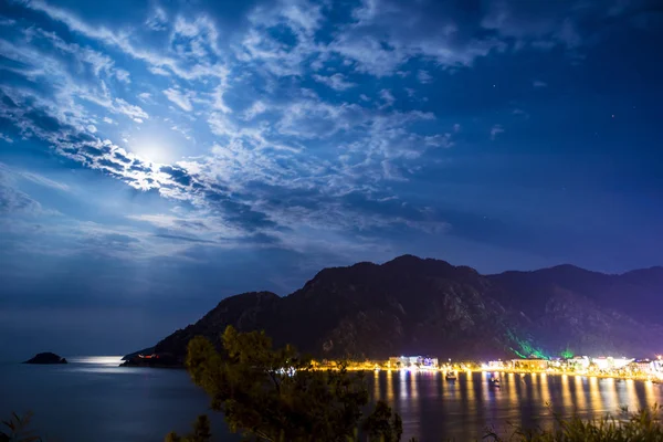 Evening view of the town of Icmeler. The bay is surrounded by mountains. Night life. Beach illuminated by evening lights